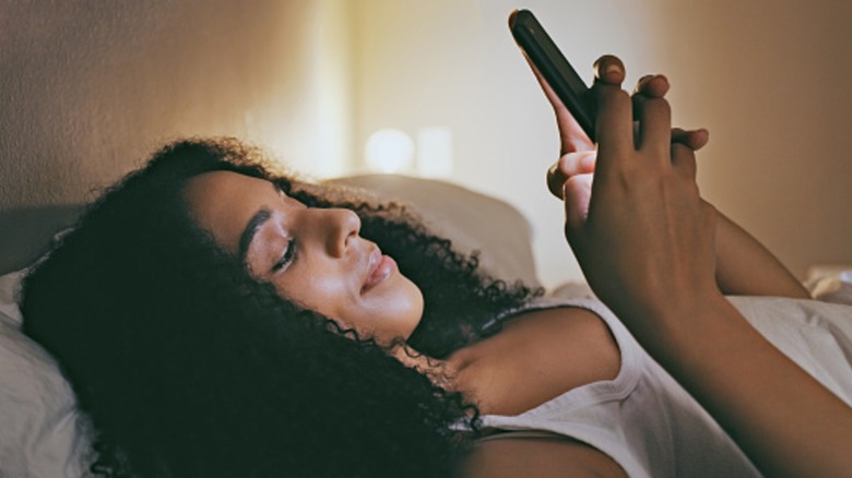 A woman in bed looking at her phone