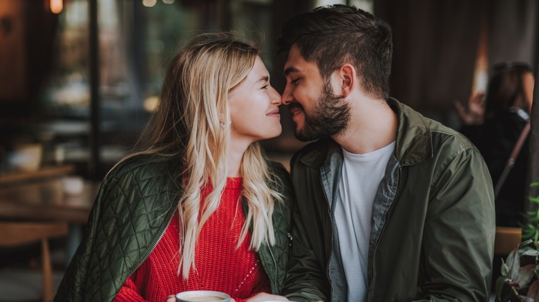 A couple sitting at a table together and rubbing noses