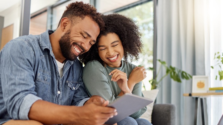 A couple smiling while looking at an ipad