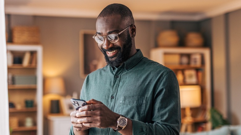 A man smiling while looking at his phone