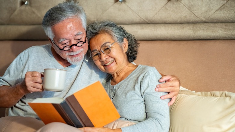 An older couple sitting in bed and reading a book together