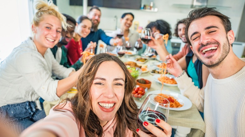 A group of friends sitting at a table and eating spaghetti together