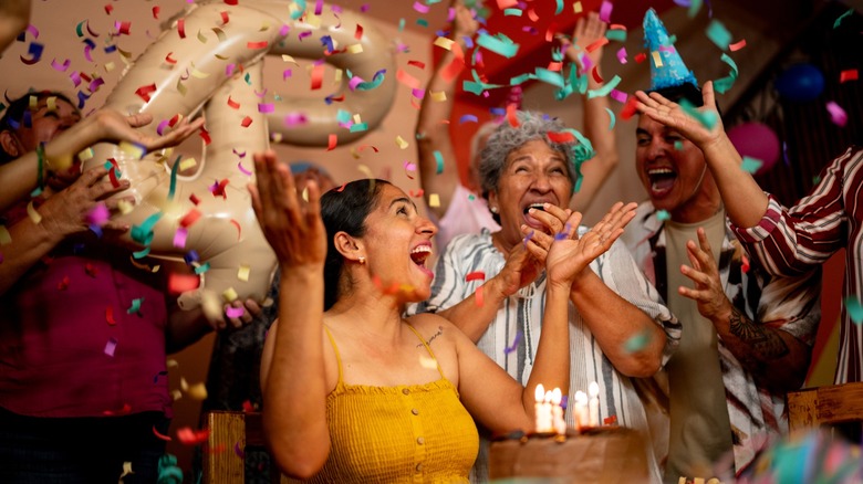 A woman celebrating her birthday with family and friends as confetti falls