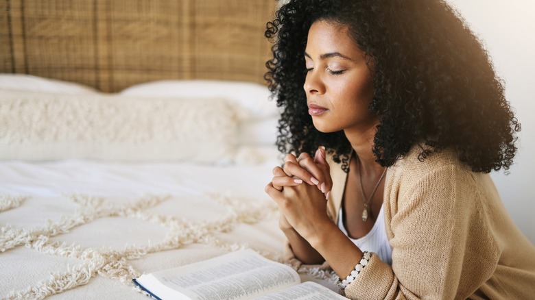 A woman praying while reading a book