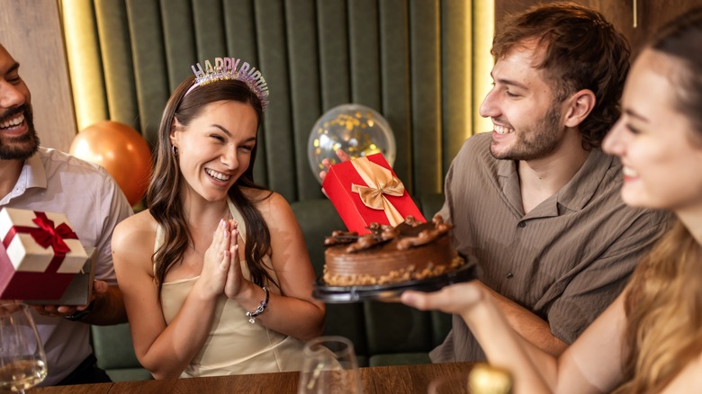 A woman being given cake and a gift on her birthday