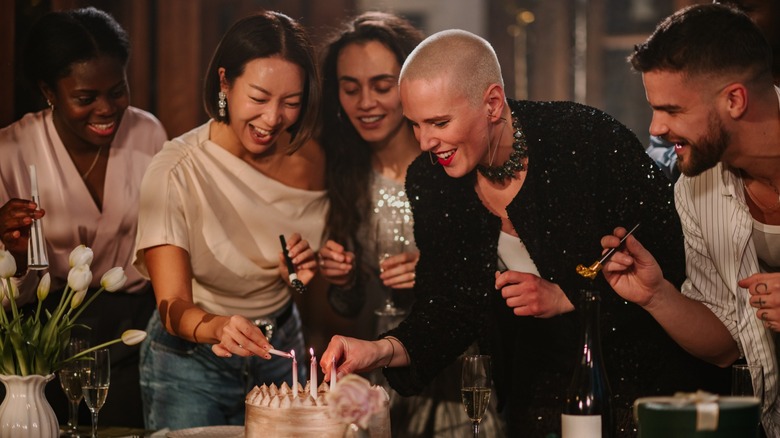 A group of friends standing around a birthday cake