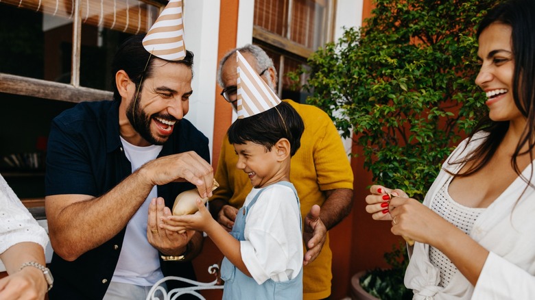 A family smiling and holding a balloon during a children's birthday party