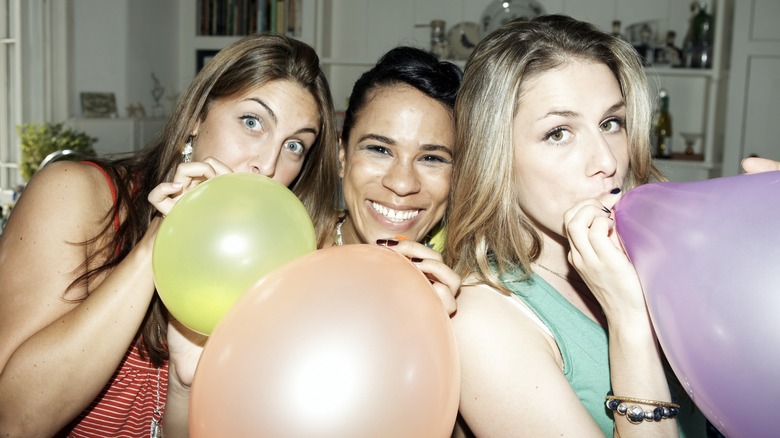 Three friends blowing up balloons together