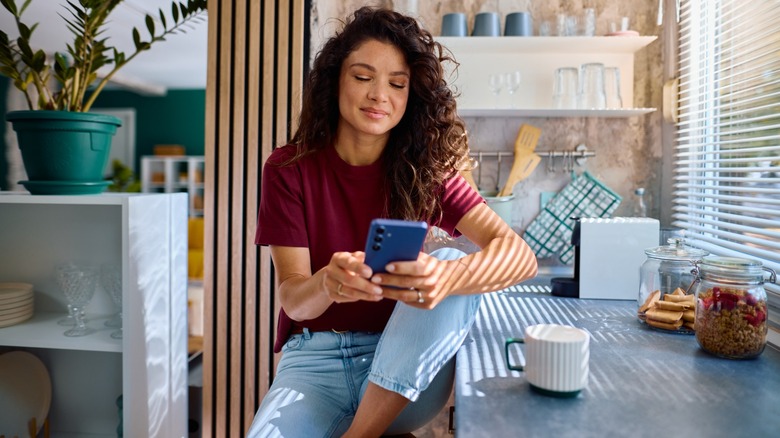 A woman slightly smiling while looking at her phone