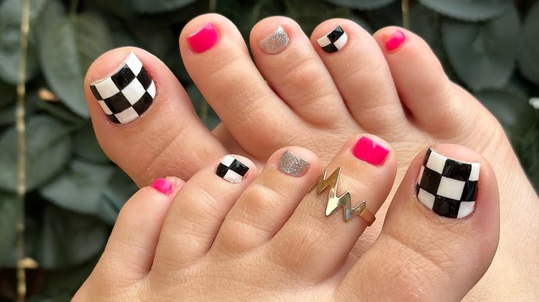 Mismatched gel pedicure with checker print, glitter, and hot pink