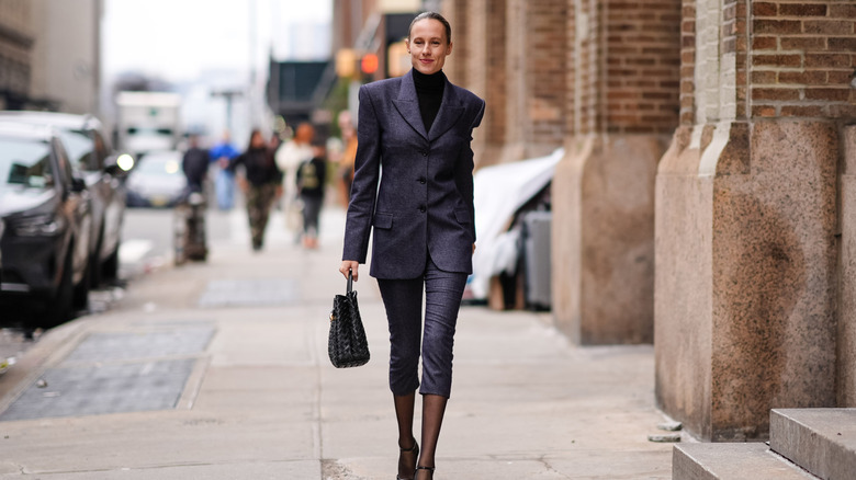 A woman in a gray blazer, matching capris and black tights
