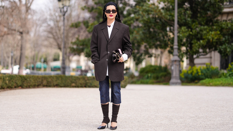 A woman wearing capris and mules with a blazer and sunglasses