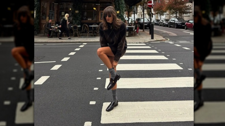 Julie Sergent Ferreri pulls up her gray socks wearing a brown jacket and black loafers