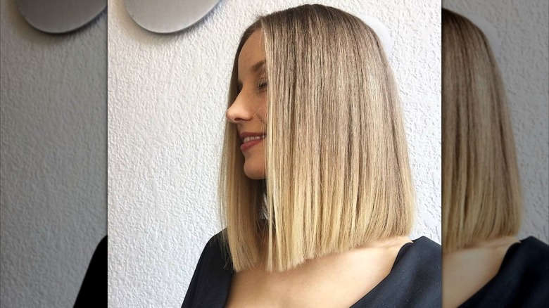 A woman with shoulder-length blonde hair that is styled straight