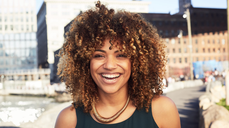 A smiling woman with curly hair that is shoulder length