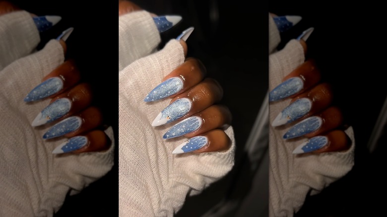 Closed-hand showing a blue cat-eye nail with wintery drawings