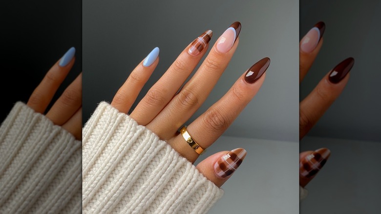 Hand showing a blue-and-brown nail design featuring two plaid nails and a layered French tip