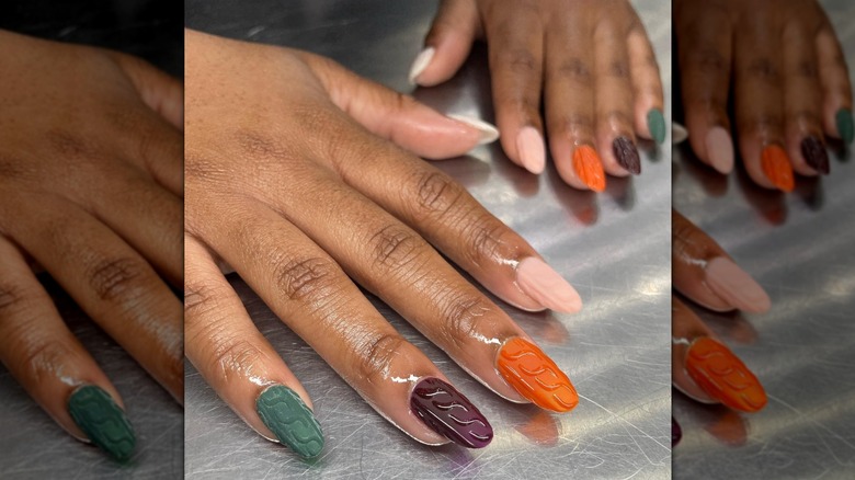 Two hands laying on a metal surface, showing multi-colored, 3D sweater designs