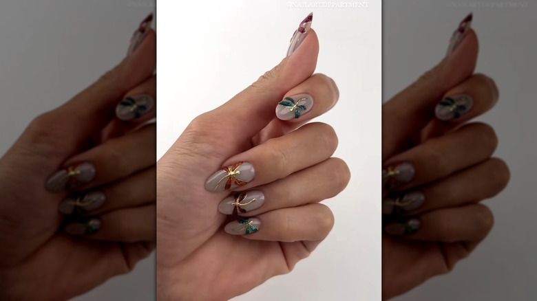 Closed hand showing a nail set with stained-glass dragonflies against a nude base color