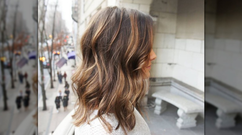 A woman with brown hair and chestnut highlights looking to the side