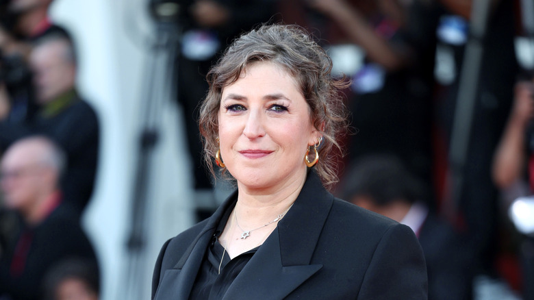 Mayim Bialik wearing a black suit on a red carpet
