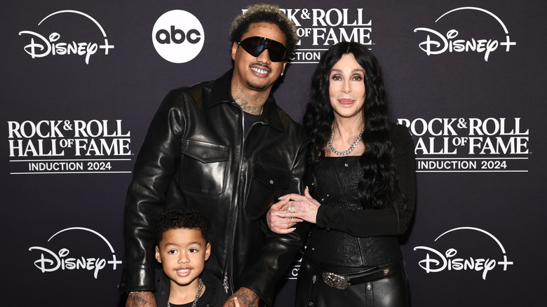 Cher links arms with Alexander Edwards who stands with his son