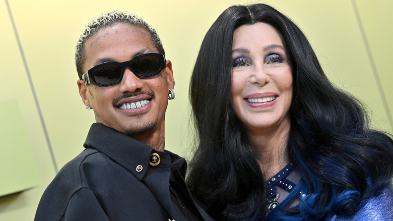 Cher smiles while wearing blue eyeshadow, next to Alexander Edwards