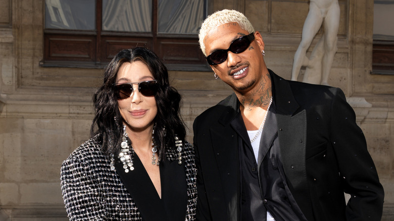 Cher stands with Alexander Edwards, both wearing sunglasses