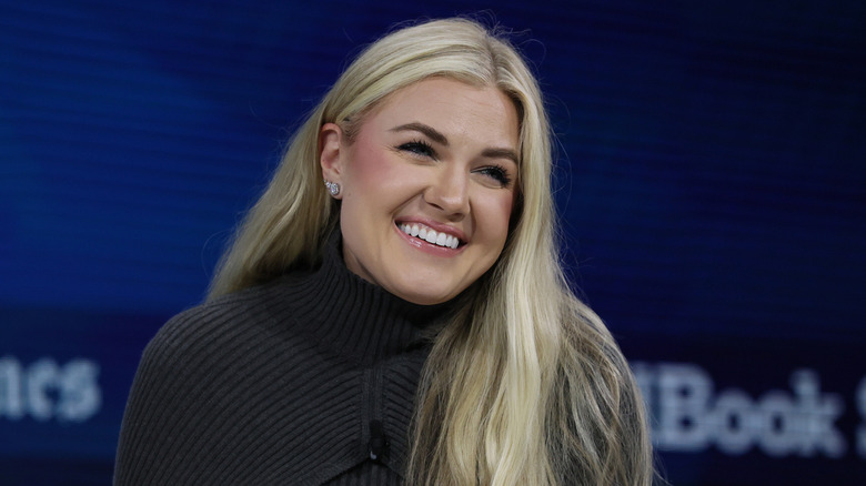 Erika Kirk smiling away from the camera in a black sweater