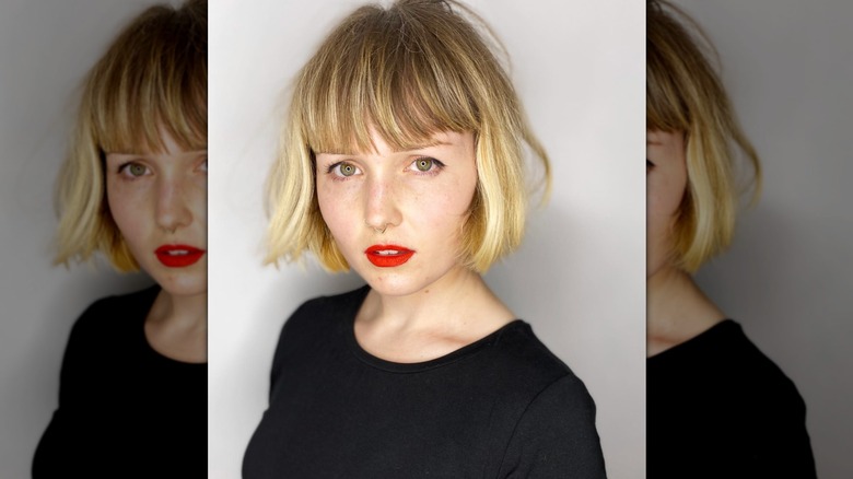A blonde woman with a blunt bob and bangs looking at the camera