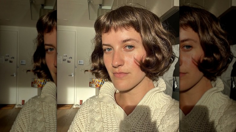 A woman with brown hair cut into a French bob with baby bangs