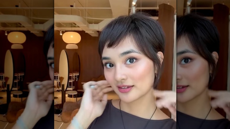A woman with brown hair cut into a pixie style looking into the camera