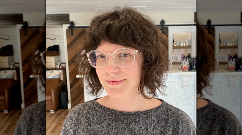 A woman with brown, curly hair looking at the camera