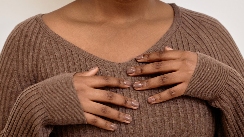Woman posing with brown nails against her brown sweater
