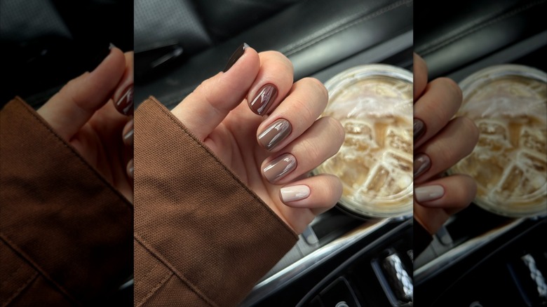 Folded hands with different shades of brown nails