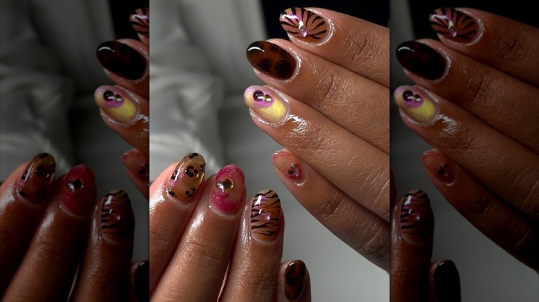 Two hands showing a warm-toned nail design featuring a combination of animal prints and cat eye effects