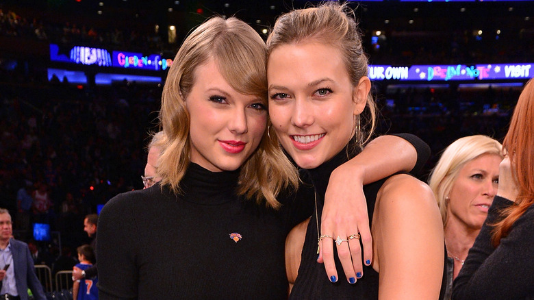 Taylor Swift and Karlie Kloss posing together at a sports game