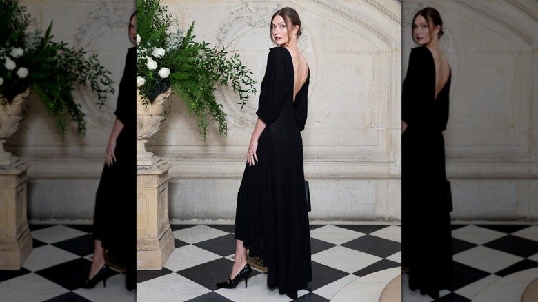 Karlie Kloss looking over her shoulder while popping her leg at a Dior photo call