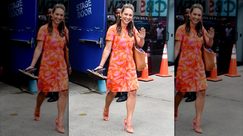 Ginger Zee waving to the camera while wearing a retro-inspired dress in pink and orange