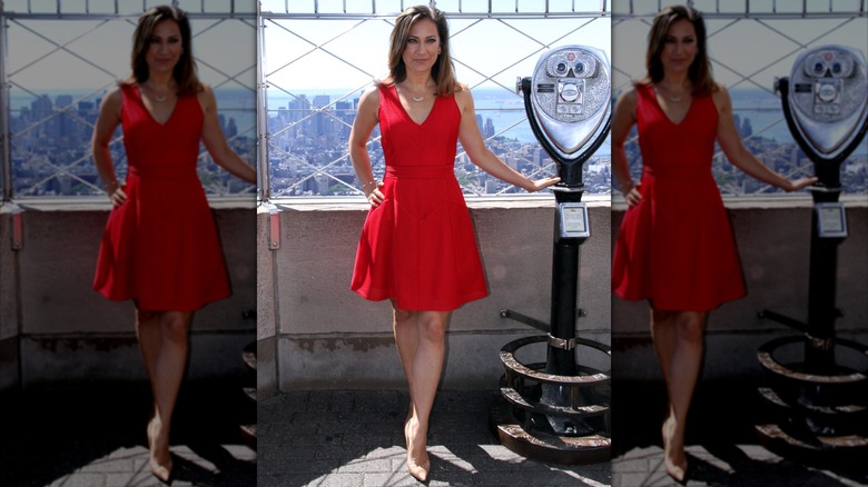 Ginger Zee at the Empire State Building while wearing a red, knee-length dress and nude heels