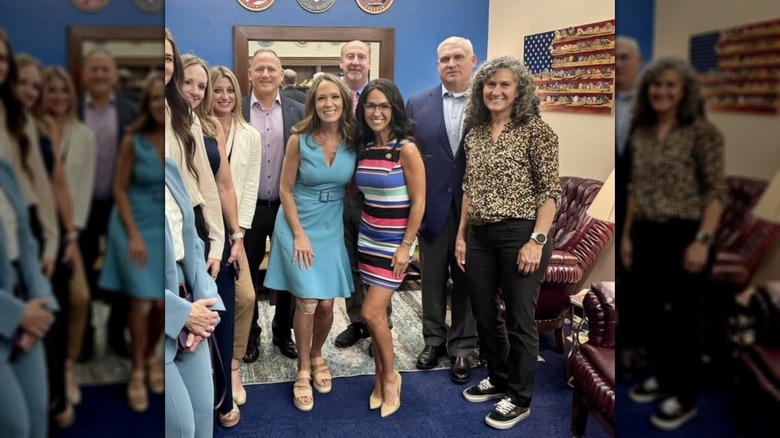 Lauren Boebert posing with several other individuals while wearing a striped dress