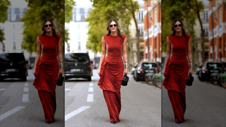 A woman walking down the street in a ruched red velvet dress