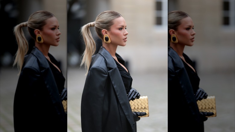 A side profile shot of a woman with a leather jacket and statement earrings