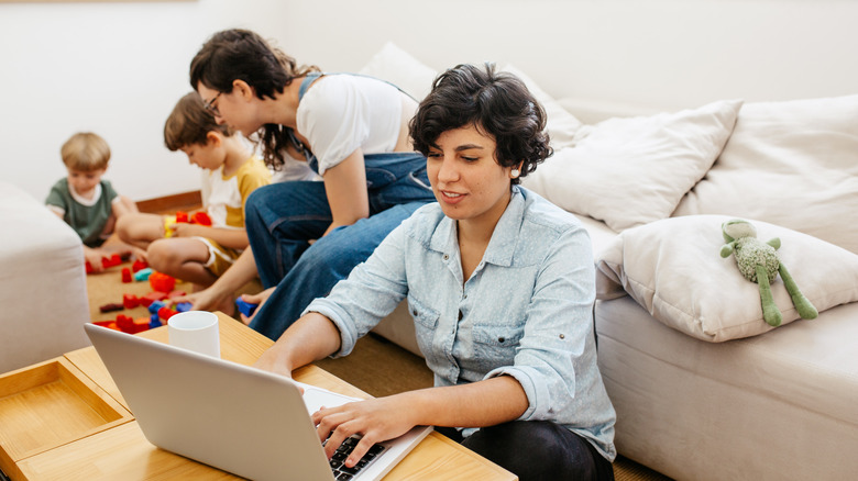 one parent works on laptop while another handles children