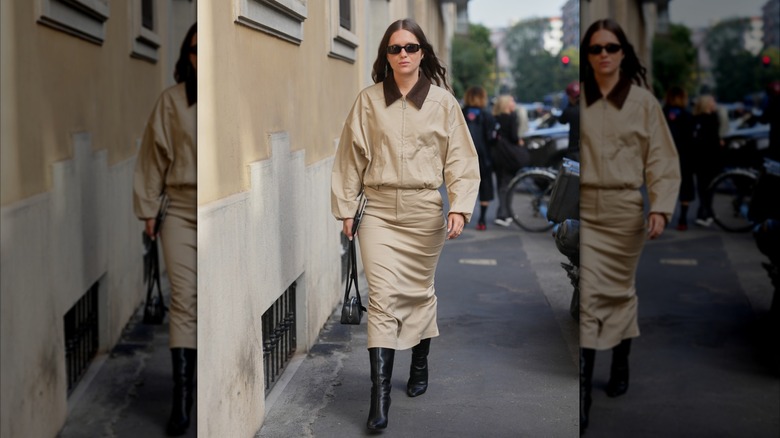 A Milan Fashion Week attendee pairs a khaki midi pencil skirt with a utility jacket and black boots