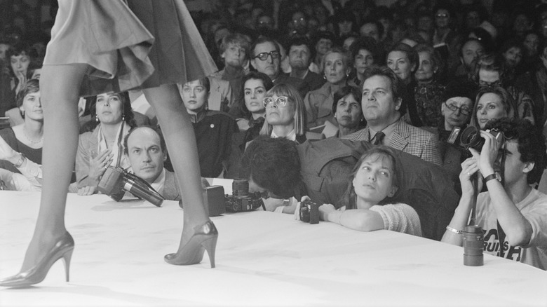 A black and white image of a woman wearing heels in front of an audience