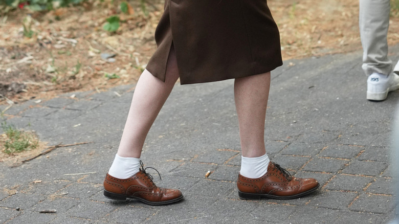 A woman wearing a brown pencil skirt and brown Oxford shoes