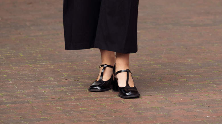 A woman wearing black trousers and black T-bar shoes