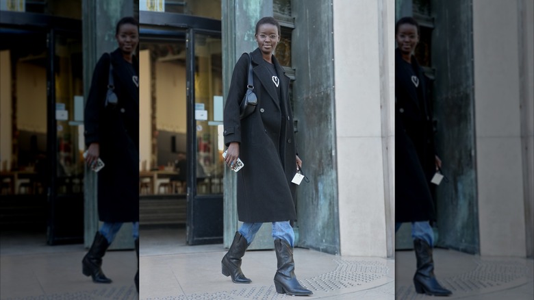 A woman in jeans with a black coat and black cowboy boots