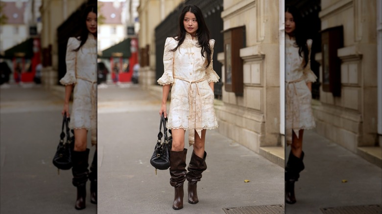A woman in a cream dress and slouchy boots